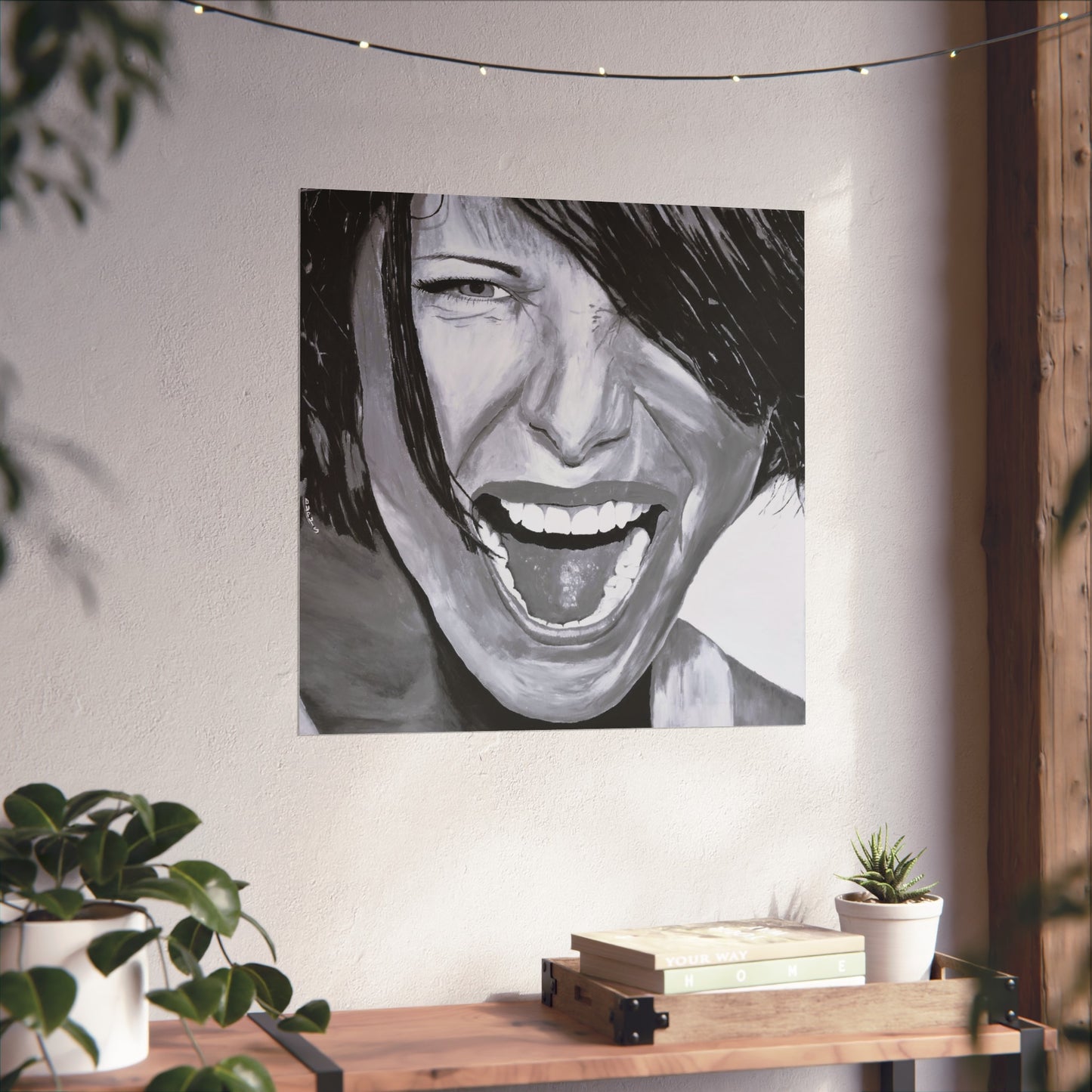 Black and White giclee art print of a passionate woman showing emotion, hanging on a wall over a wooden table next to a plant