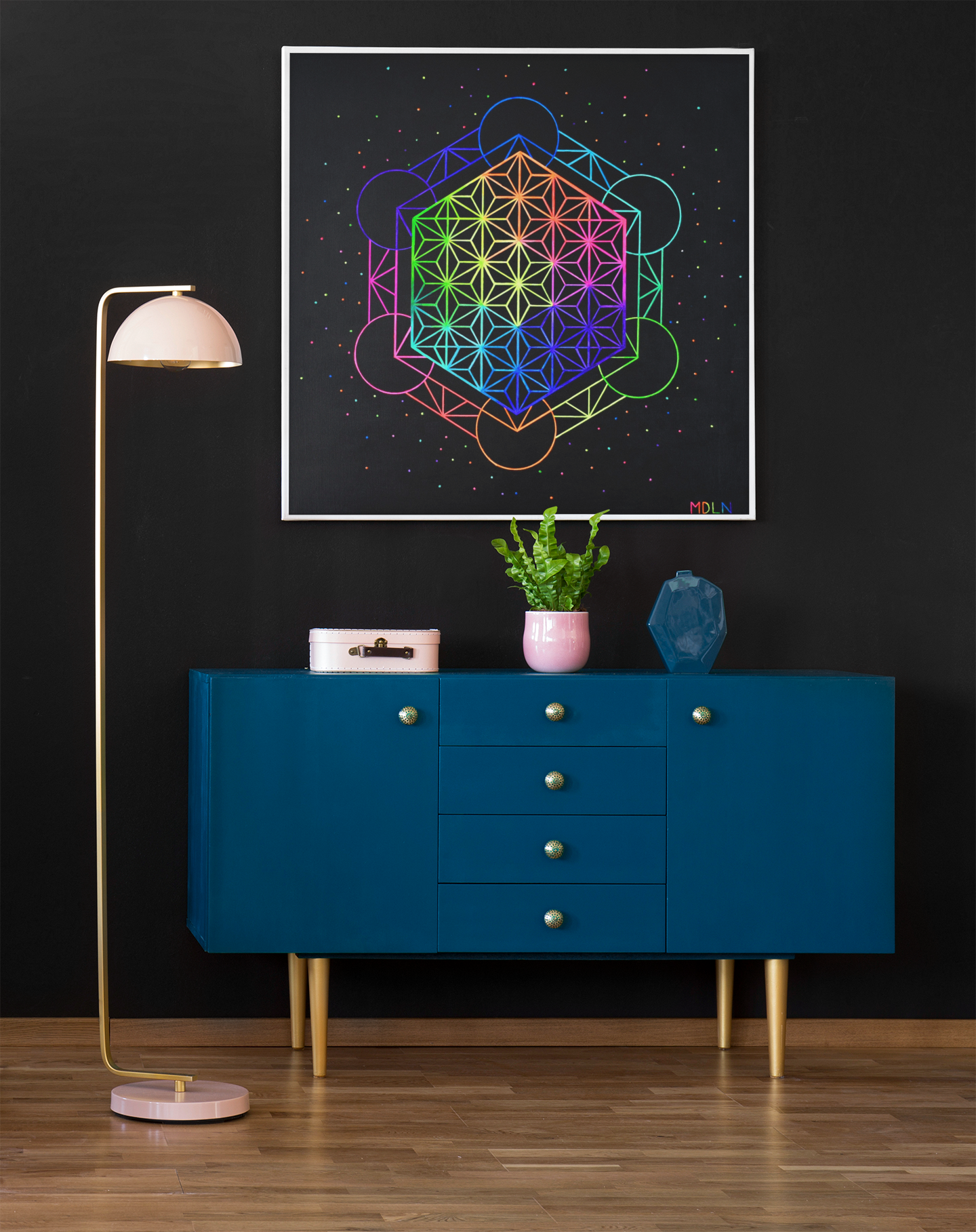 A big and colorful sacred geometry art print on canvas of Metatrons cube and the flower of life sacred geometry, hanging on a wall over a console table next to a lamp