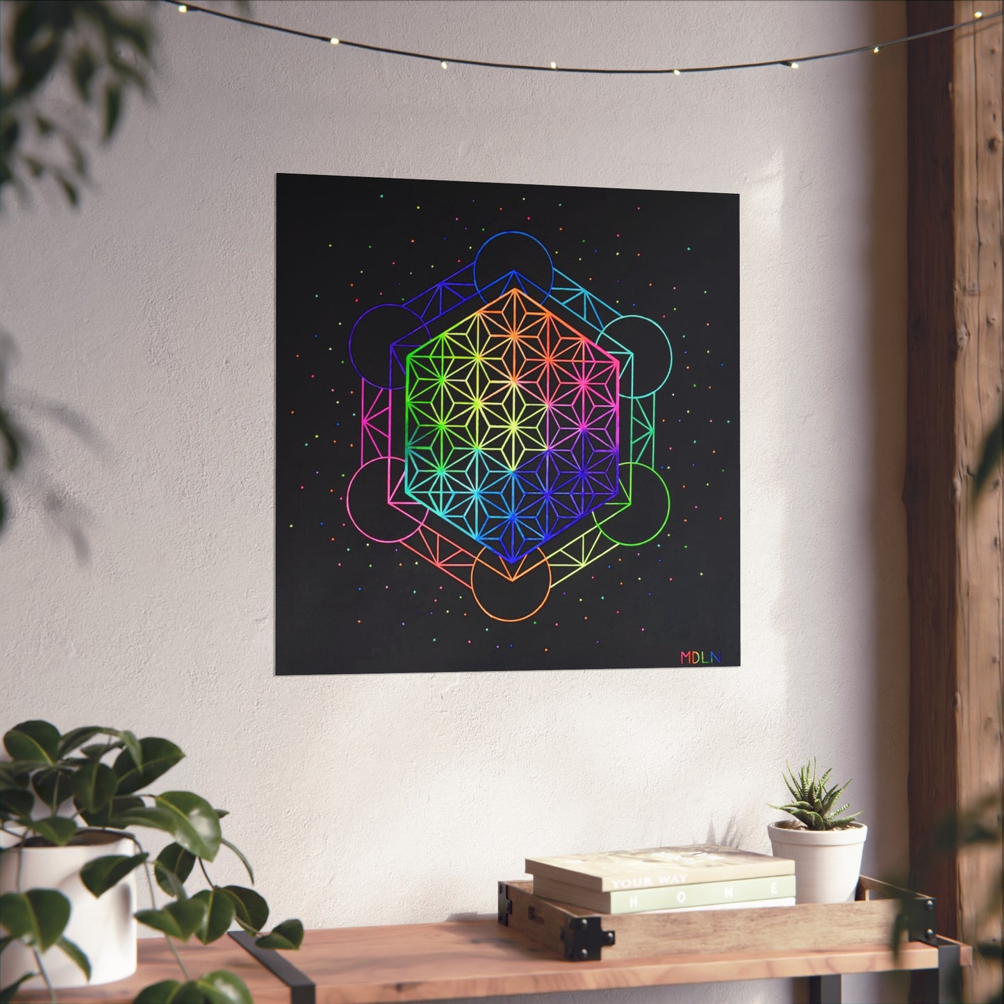 A beautiful sacred geometry giclee art print of Metatrons cube sacred geometry overlayed with the flower of life sacred geometry mandala, hanging on a wall over a wooden table next to a plant