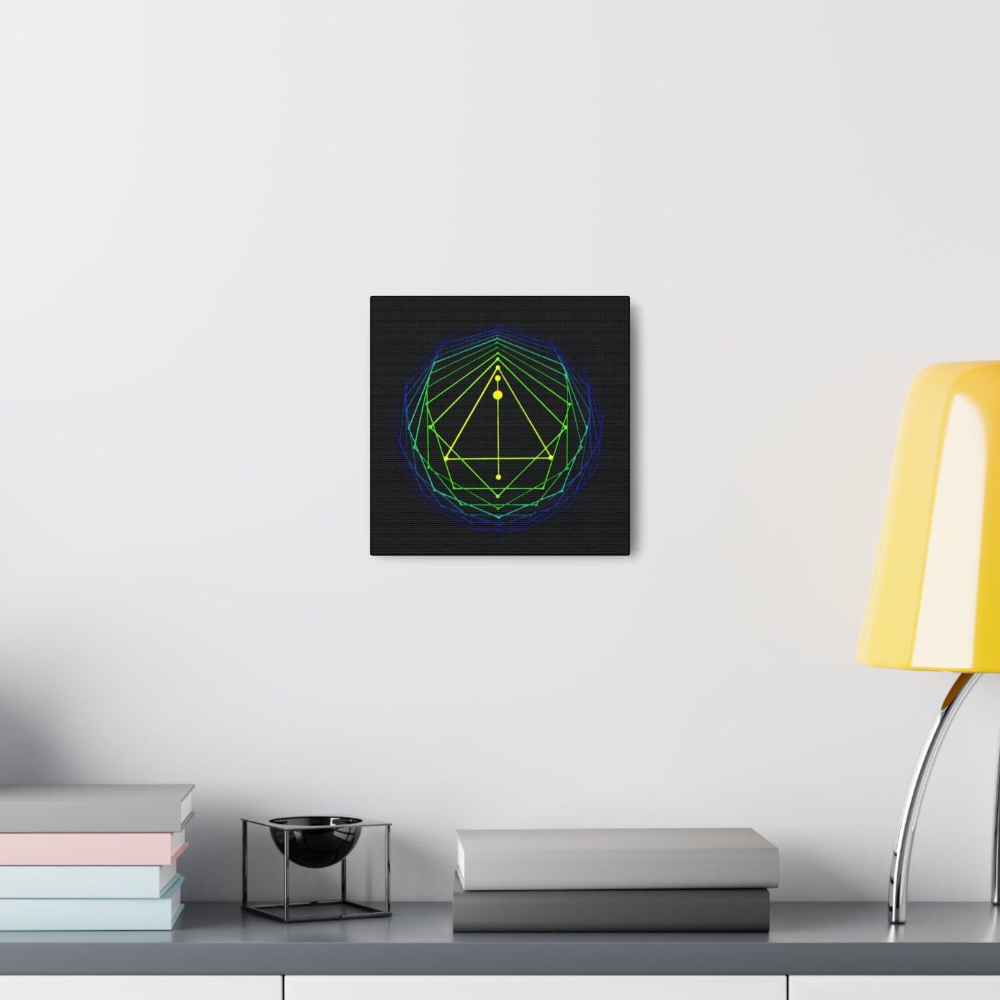 canvas print of an original acrylic painting of sacred geometry in blue/green/yellow tones, hanging on a wall over a desk