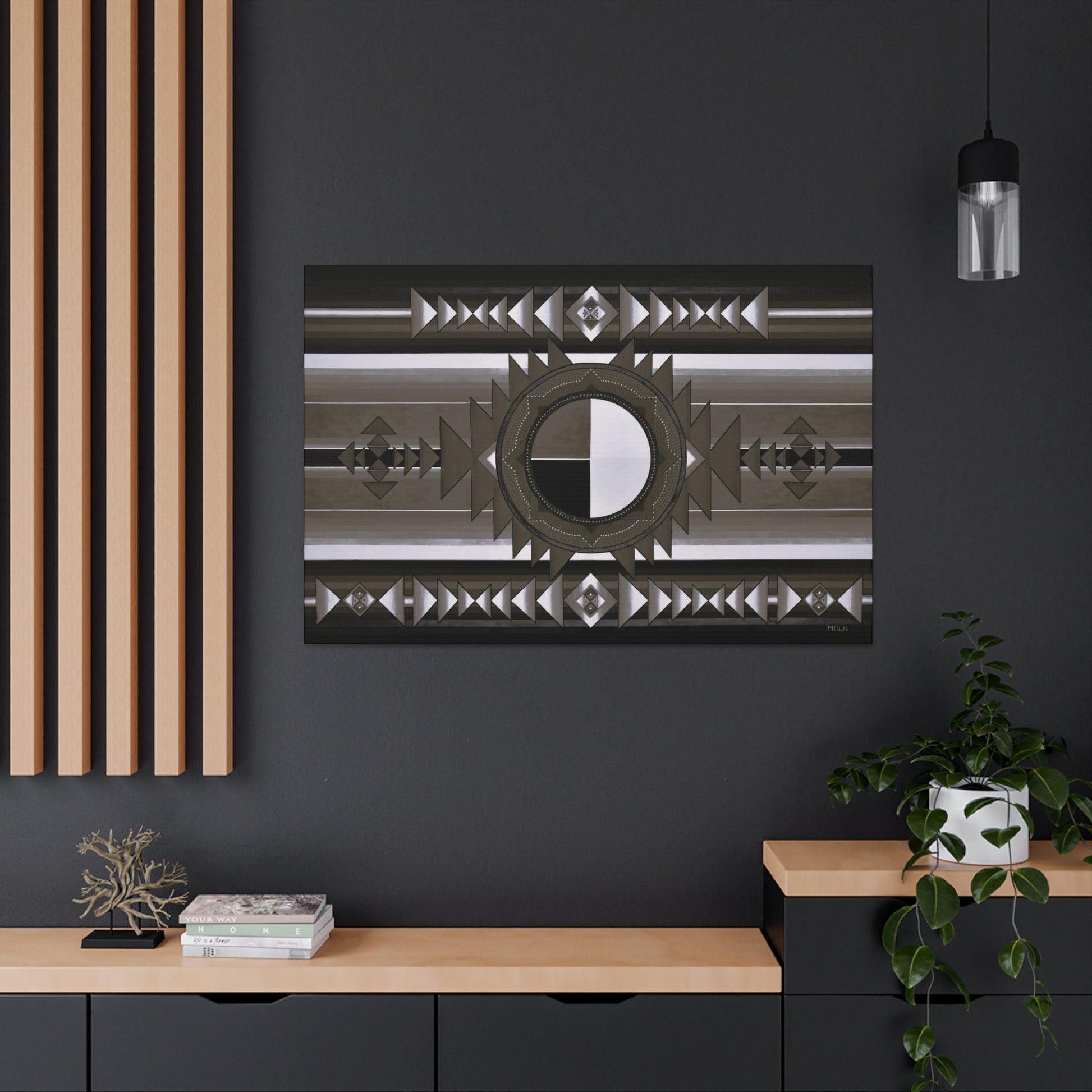 A black and white Indigenous Medicine Wheel art print on canvas hanging on a black office wall