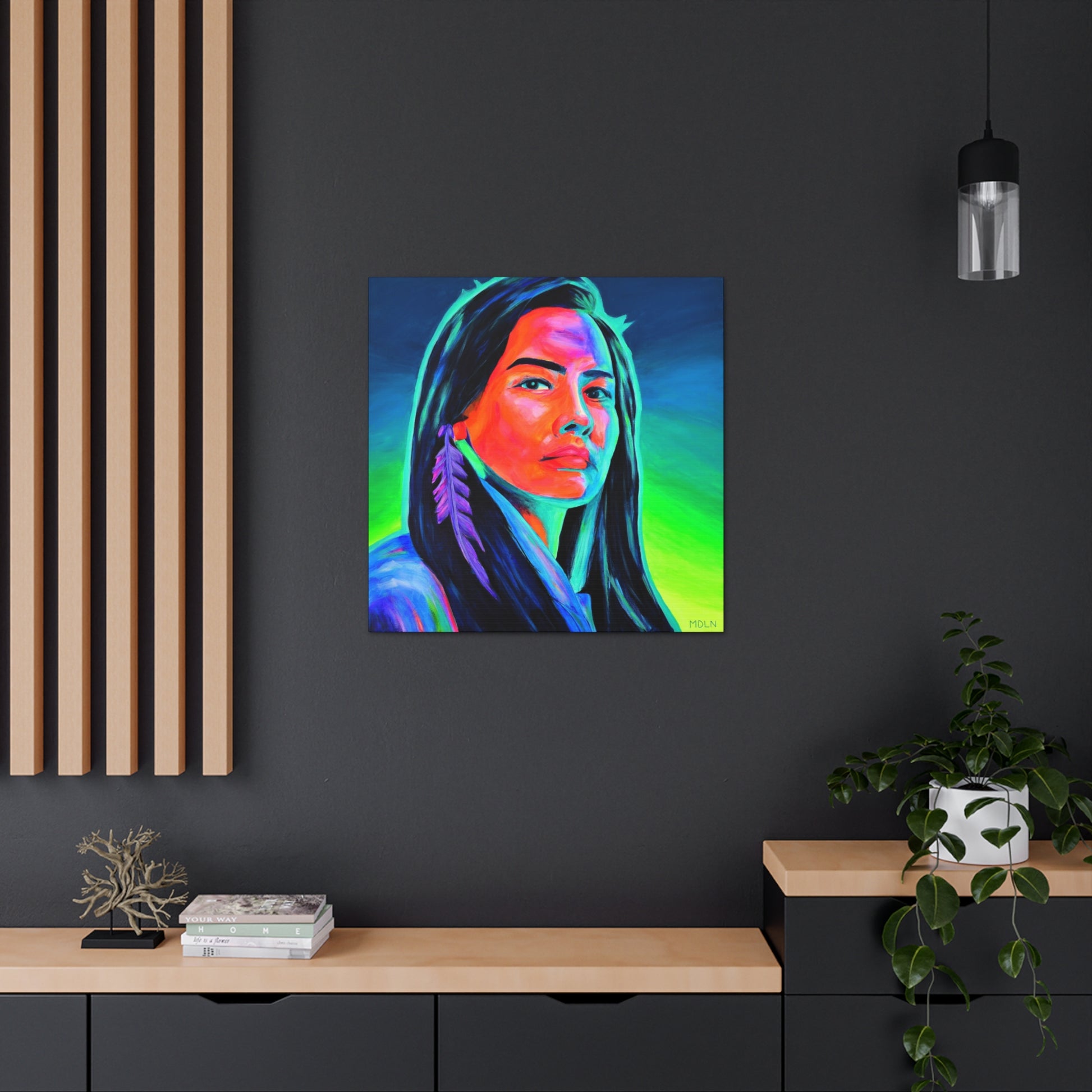 Colorful Indigenous art print on canvas of an Aboriginal Woman with feather earring, hanging on a black wall in an office