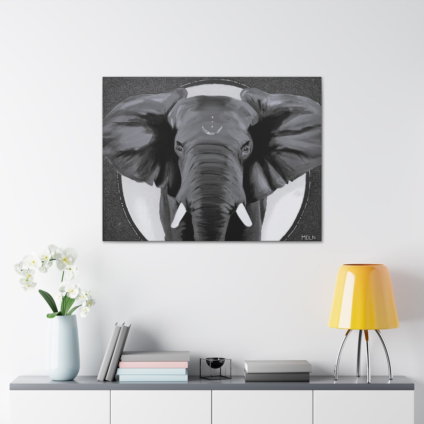 Black and white African elephant art print on canvas hanging on the wall over a console table with yellow lamp