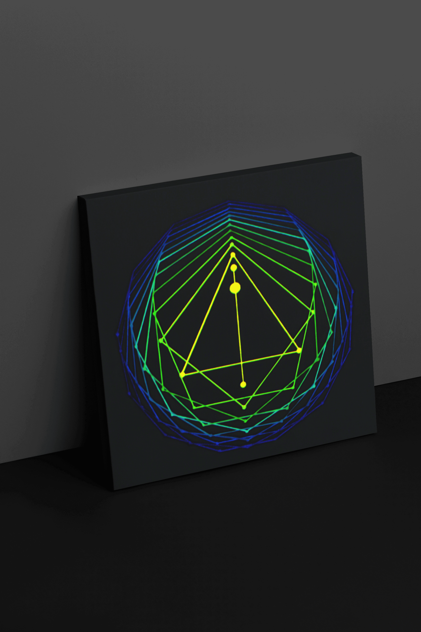 canvas print of an original acrylic painting of sacred geometry in blue/green/yellow tones leaning against a wall 