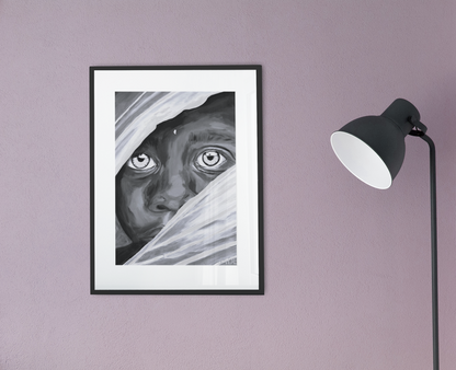 A black and white giclee art print of an African Boy hanging on a wall in a black frame with white matting next to a black lamp