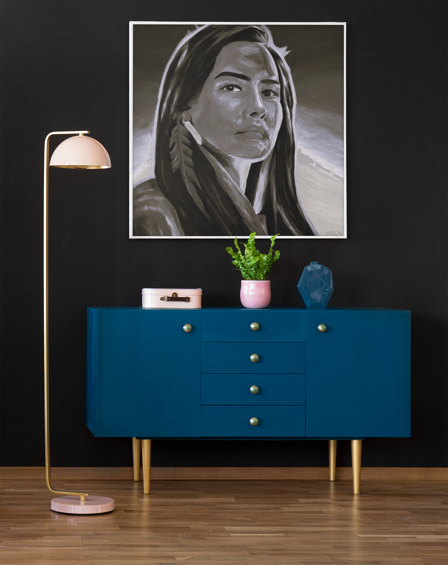 Black and white Indigenous art print on canvas of an Aboriginal Woman with feather earring, hanging the wall over a console table next to a lamp