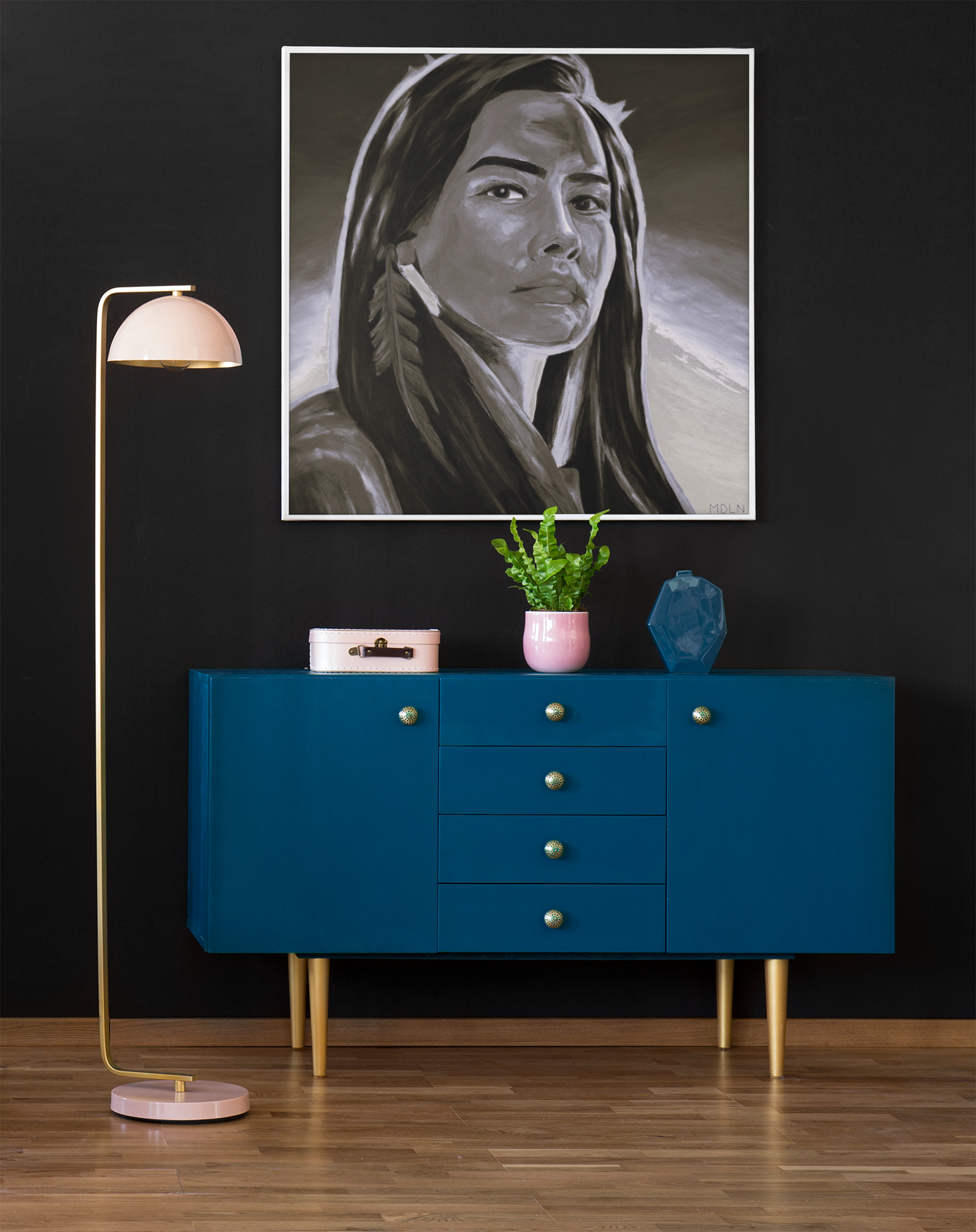 Black and white Indigenous giclee art print of a strong Aboriginal Woman with feather earring, hanging on the wall over a credenza next to a lamp