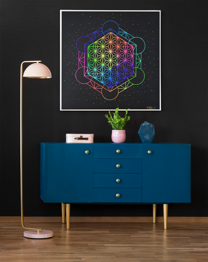 A big and colorful sacred geometry giclee art print of Metatrons cube art overlayed with the flower of life mandala art, hanging on a wall over a cabinet next to a lamp