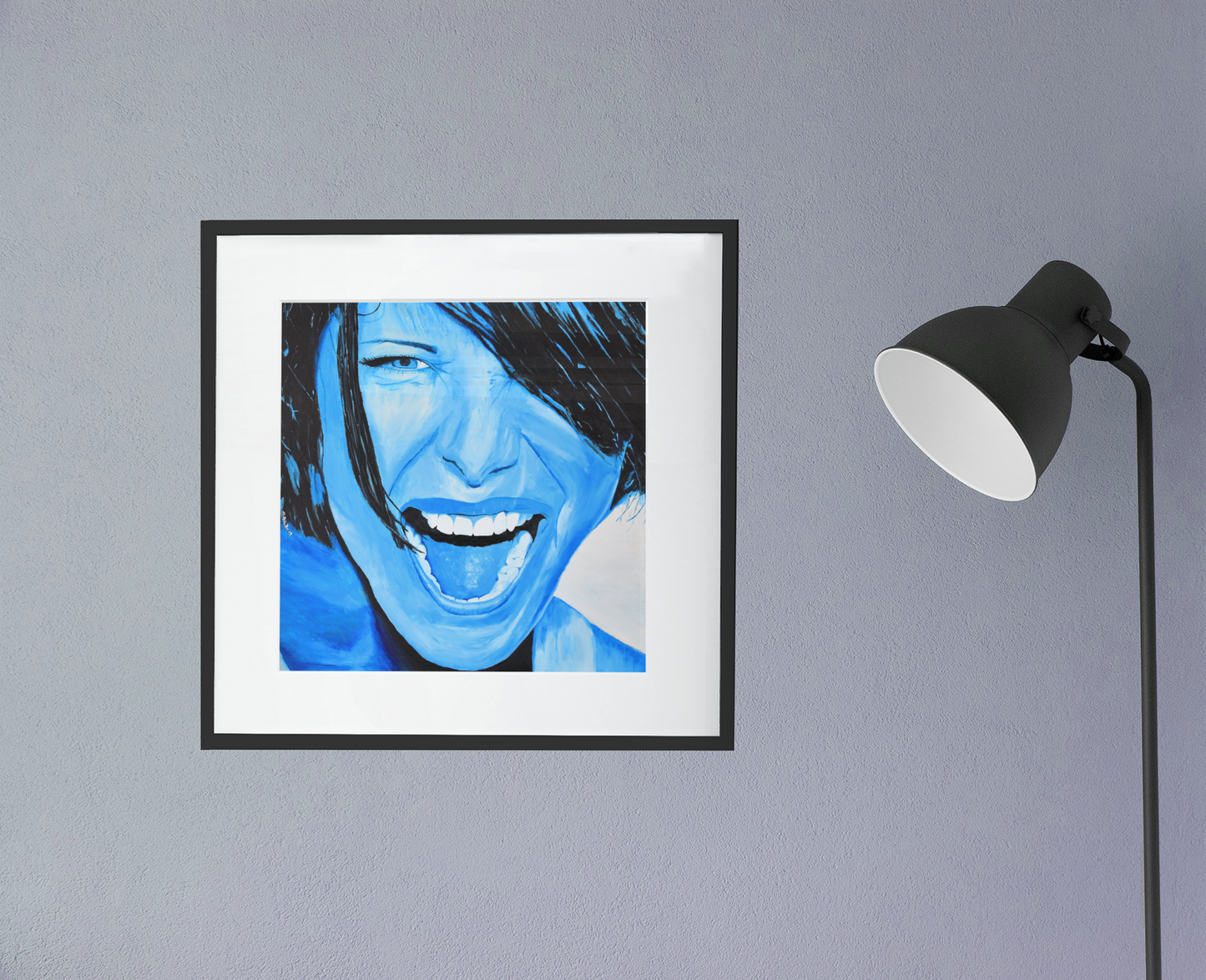 A bright blue giclee art print of a passionate woman showing emotions, woman portrait art, framed in black with white matting, hanging on a wall next to a lamp