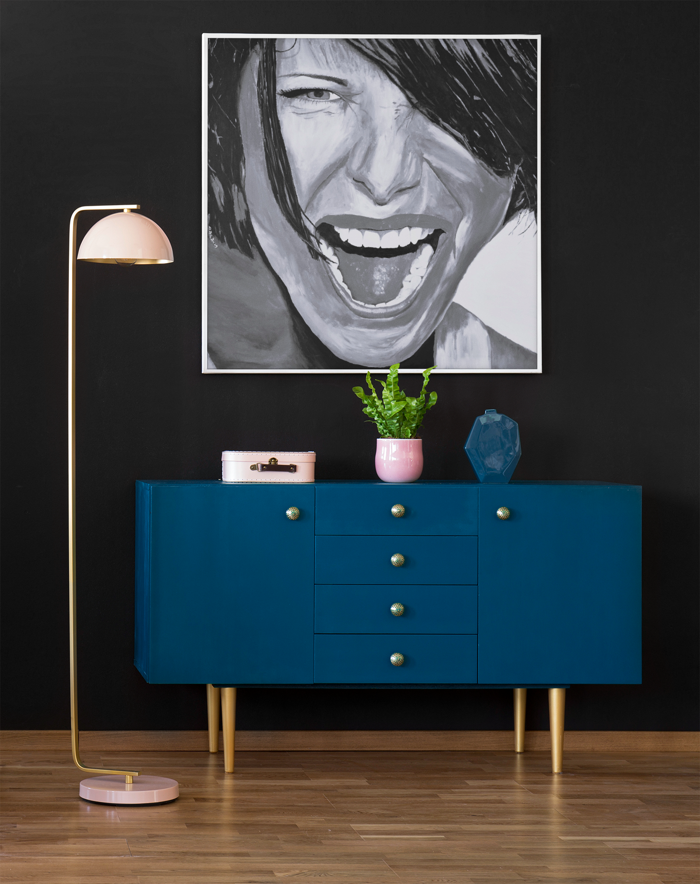 A large Black and White giclee art print of a passionate woman showing emotion, hanging on a wall over a cabinet next to a lamp