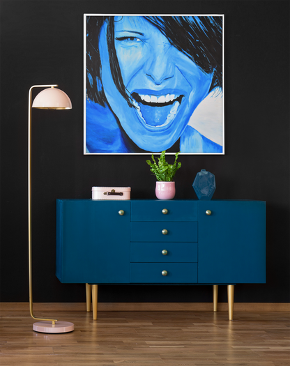 An art print on canvas of a passionate woman showing emotions, painted in  bright blue, hanging on a wall over a cabinet next to a lamp, woman portrait art