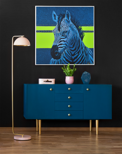 A bright and bold giclee art print of a majestic zebra painting with blue and neon yellow abstract background, zebra art hanging on a wall over a cabinet next to a lamp